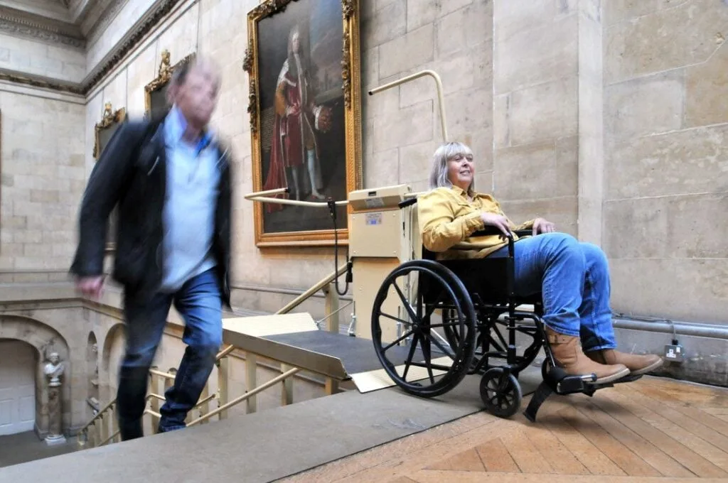 A wheelchair user travelling on the platform stairlift inside Castle Howard