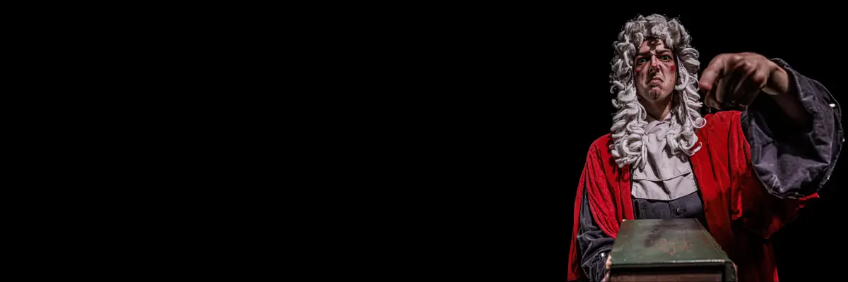 A performer in a dark theatrical scene at The Edinburgh Dungeon