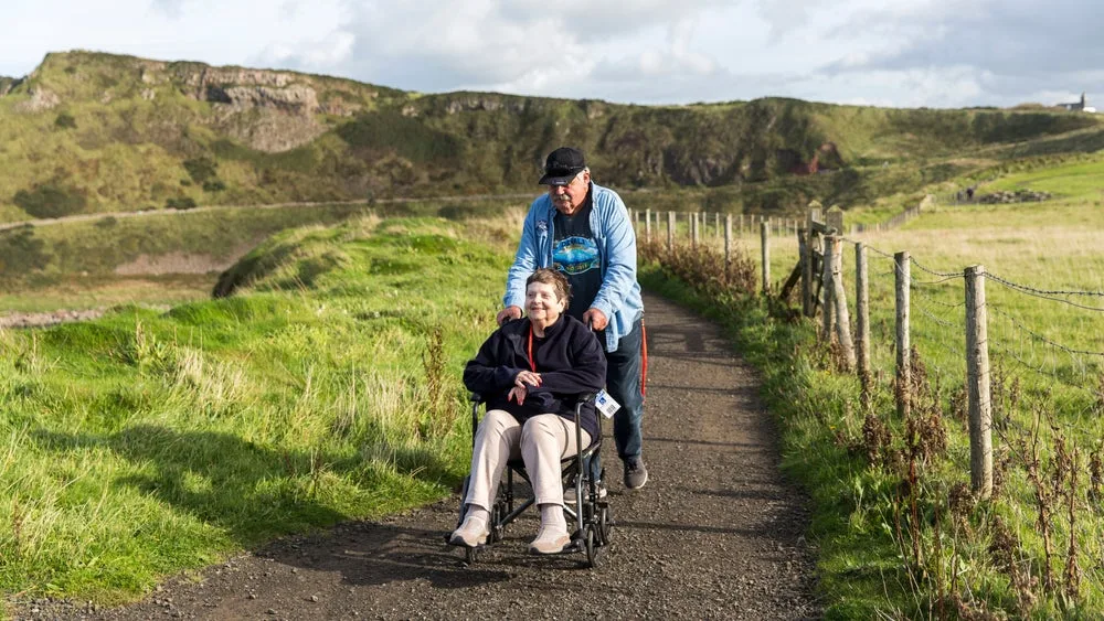 A visitor using a wheelchair with a companion on an accessible path at Giant's Causeway