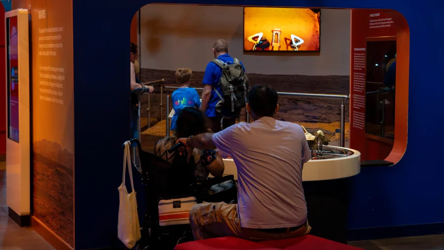 A wheelchair user and families exploring the Our Solar System gallery during an Accessible Afternoon at the National Space Centre